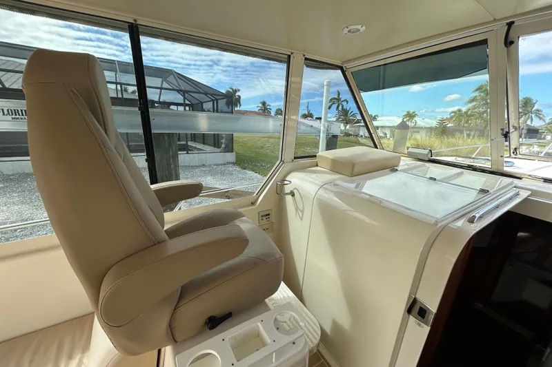 Slide: The Image of 2008 Mainship Pilot 34 helm view with marina backdrop. - 56