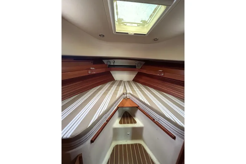 Slide: The Image of 2008 Mainship Pilot 34 cabin interior with striped bedding and wooden accents. - 6