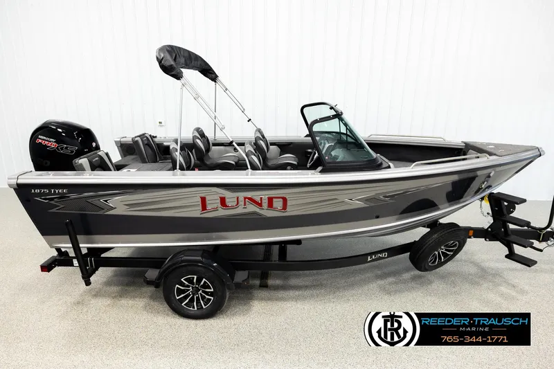 The Image of 2026 Lund 1875 Tyee boat on trailer, side view, in showroom setting. - 1