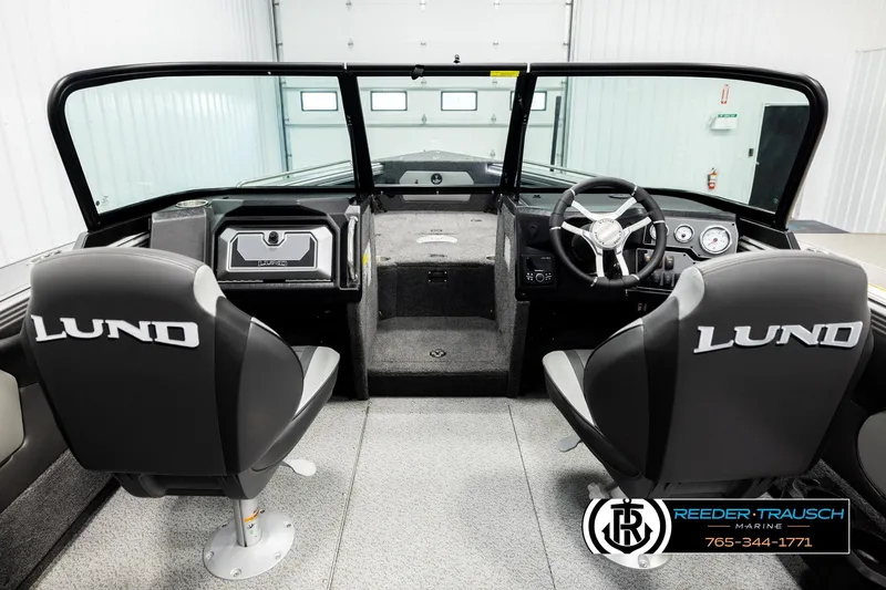 Slide: The Image of 2026 Lund 1875 Tyee boat interior with steering wheel and branded seats in showroom. - 13
