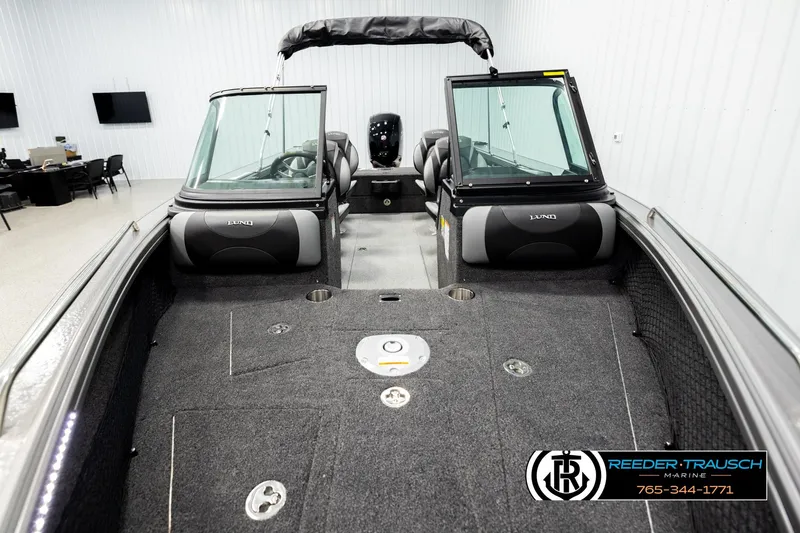 Slide: The Image of 2026 Lund 1875 Tyee boat interior with seating and dashboard, displayed in showroom. - 16