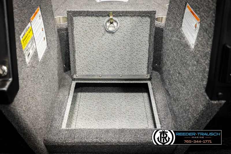 Slide: The Image of Open storage compartment in 2026 Lund 1875 Tyee boat, featuring carpeted interior and safety labels. - 28
