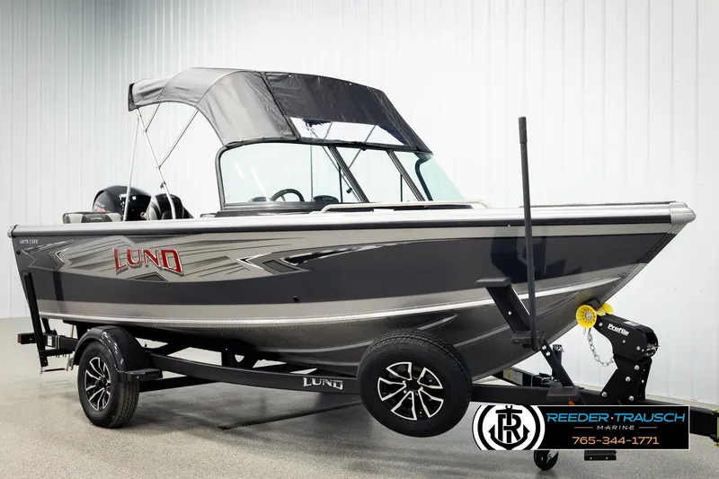 Slide: The Image of 2026 Lund 1875 Tyee boat with canopy on trailer, displayed indoors. - 3