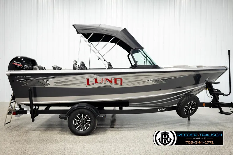Slide: The Image of 2026 Lund 1875 Tyee boat with canopy on trailer, displayed indoors. - 4