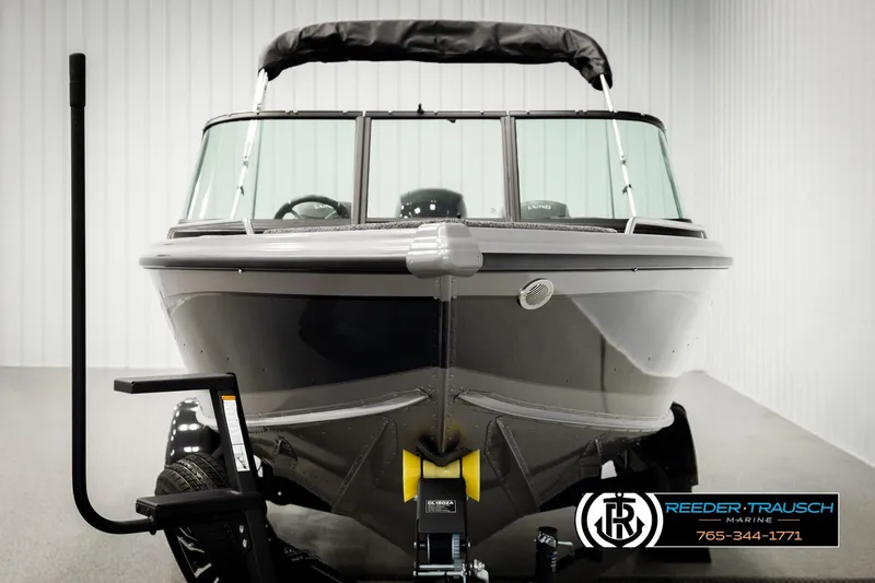 Slide: The Image of 2026 Lund 1875 Tyee boat on trailer in showroom, Reeder-Trausch Marine branding visible. - 7