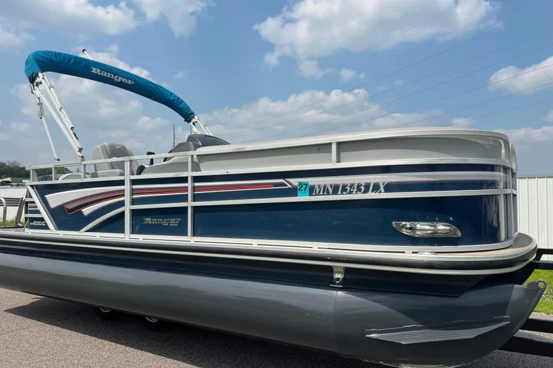 The Image of 2019 Ranger Reata 200C pontoon boat with blue canopy and sleek design. - 0