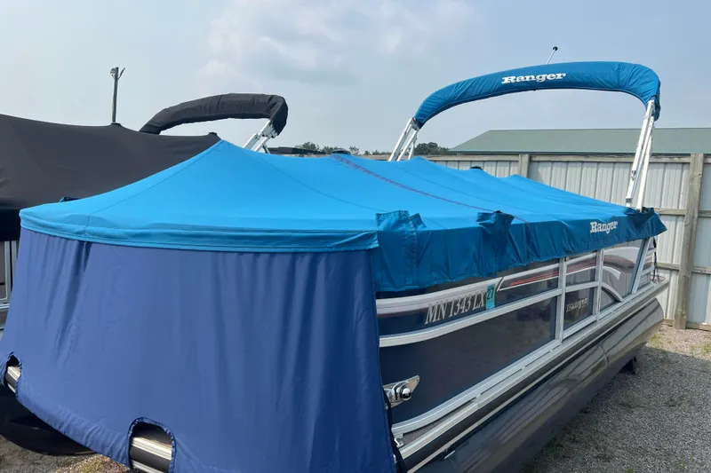 Slide: The Image of 2019 Ranger Reata 200C pontoon boat with blue cover in storage. - 56