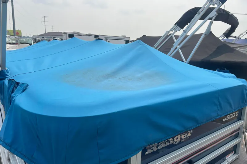 Slide: The Image of 2019 Ranger Reata 200C boat with blue cover in a marina setting. - 57