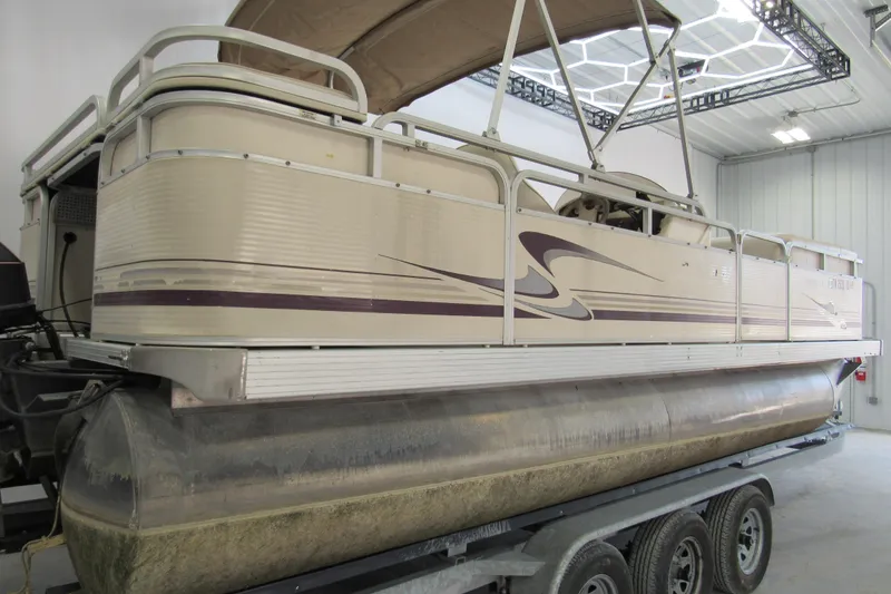 Slide: The Image of 2000 Sylvan Supreme LX pontoon boat in a garage on a trailer. - 2