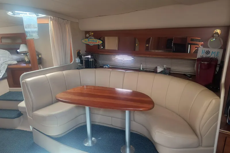 Slide: The Image of Interior of 2000 Cruisers Yachts 3575 Express with curved seating and wooden table. - 19