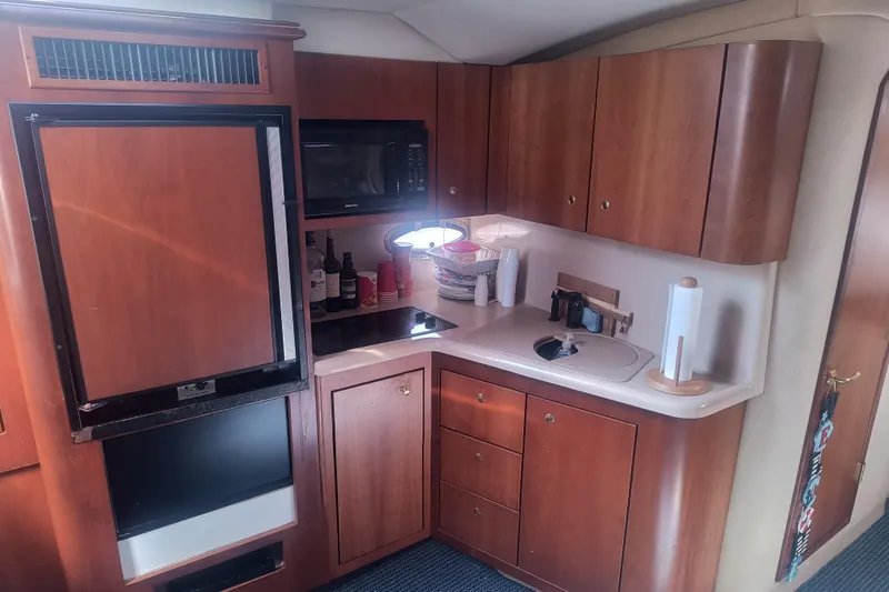 Slide: The Image of Interior of 2000 Cruisers Yachts 3575 Express, featuring a compact kitchen with wood cabinetry. - 20