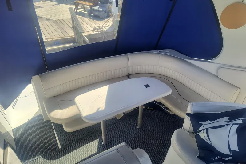 Slide: The Image of 2000 Cruisers Yachts 3575 Express interior with curved seating and table, blue canopy. - 13