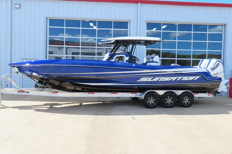 Slide: The Image of 2026 Sunsation 32CCX boat in vibrant blue on a trailer, parked outside a building. - 25