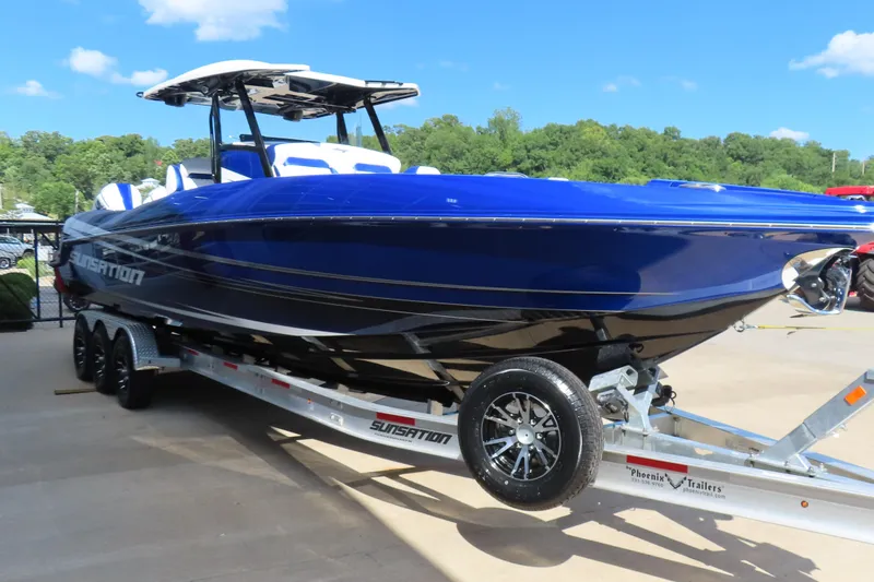Slide: The Image of 2026 Sunsation 32CCX boat in vibrant blue on a trailer, outdoors. - 4