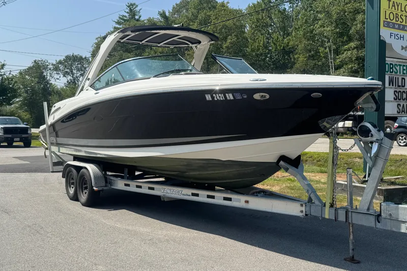 The Image of 2011 Sea Ray 270 SLX boat on trailer, parked outdoors near trees and signage. - 0