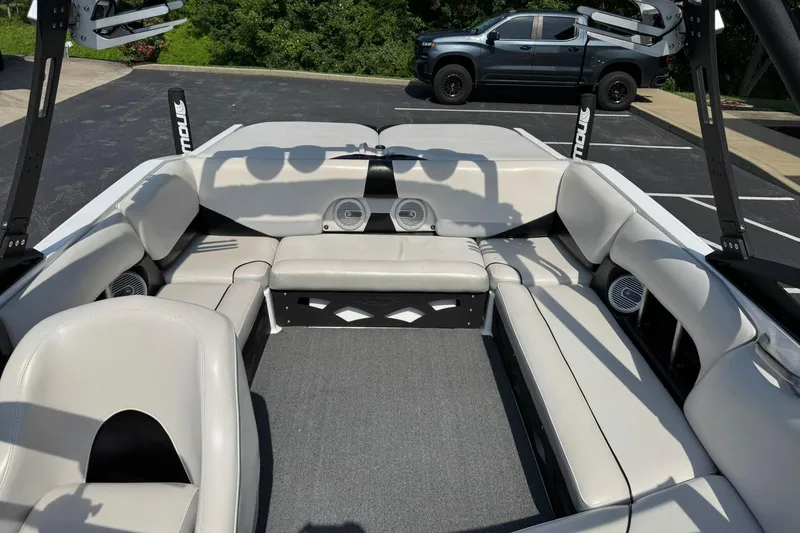 Slide: The Image of 2014 Axis A22 boat interior with gray seating and speakers, parked near a black truck. - 11