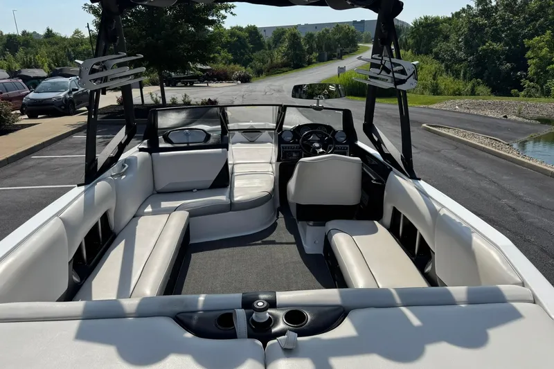 Slide: The Image of 2014 Axis A22 boat interior with white seating, parked outdoors. - 14