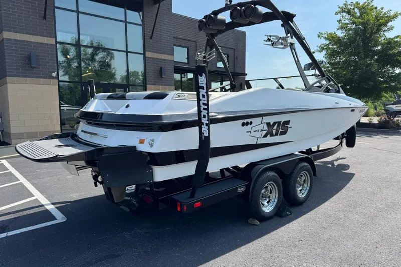 Slide: The Image of 2014 Axis A22 boat on trailer, parked near modern building. - 3