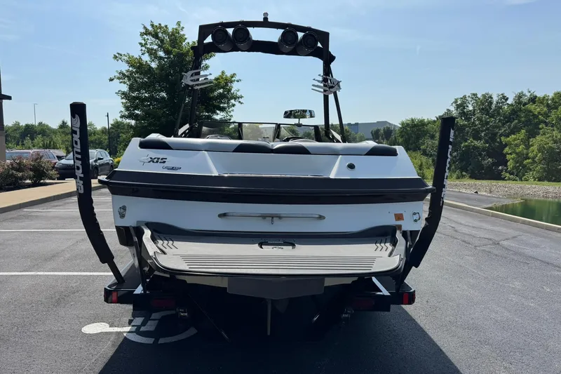 Slide: The Image of 2014 Axis A22 boat, rear view in parking lot, showcasing wakeboard tower and swim platform. - 4