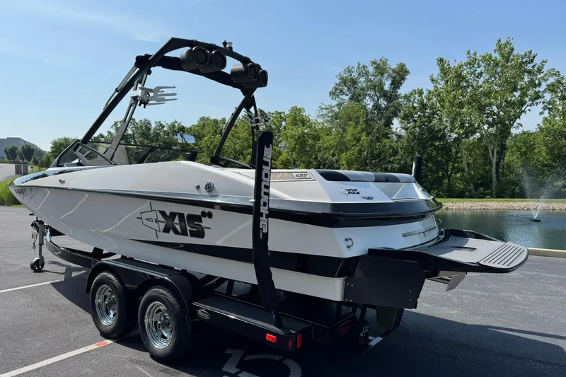Slide: The Image of 2014 Axis A22 boat on trailer near a pond, surrounded by trees. - 5