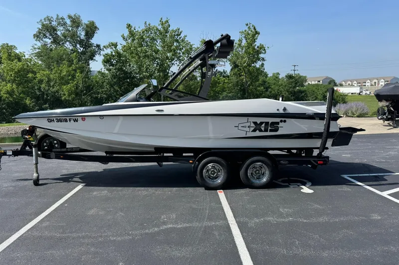 Slide: The Image of 2014 Axis A22 boat on trailer in parking lot, surrounded by trees and buildings. - 6