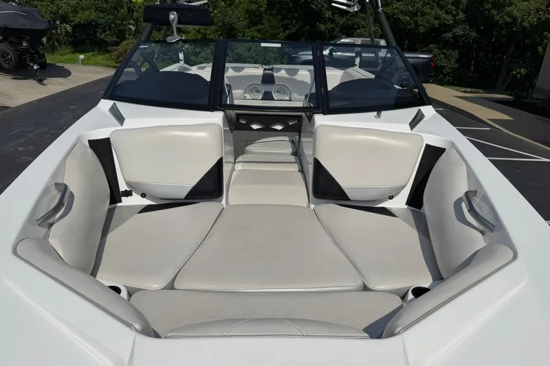 Slide: The Image of 2014 Axis A22 boat interior with white and gray seating, parked outdoors. - 7