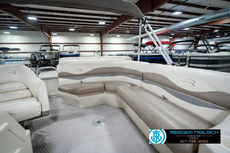 Slide: The Image of 2004 Bennington 185L pontoon boat interior with beige seating in showroom. - 21