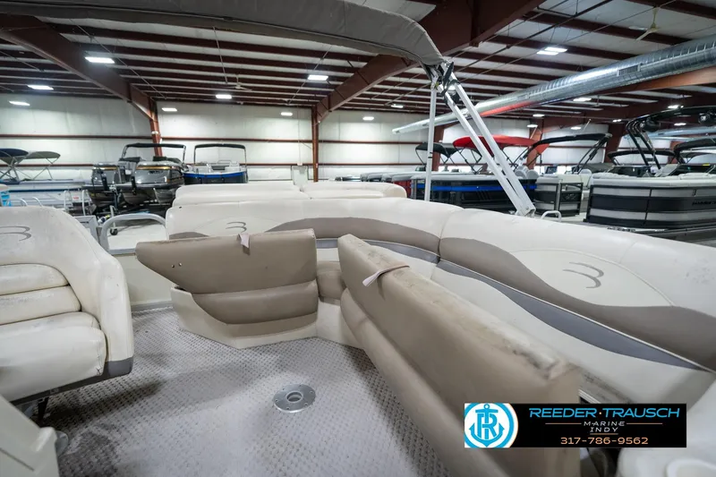 Slide: The Image of 2004 Bennington 185L pontoon boat interior with beige seating in a showroom. - 22