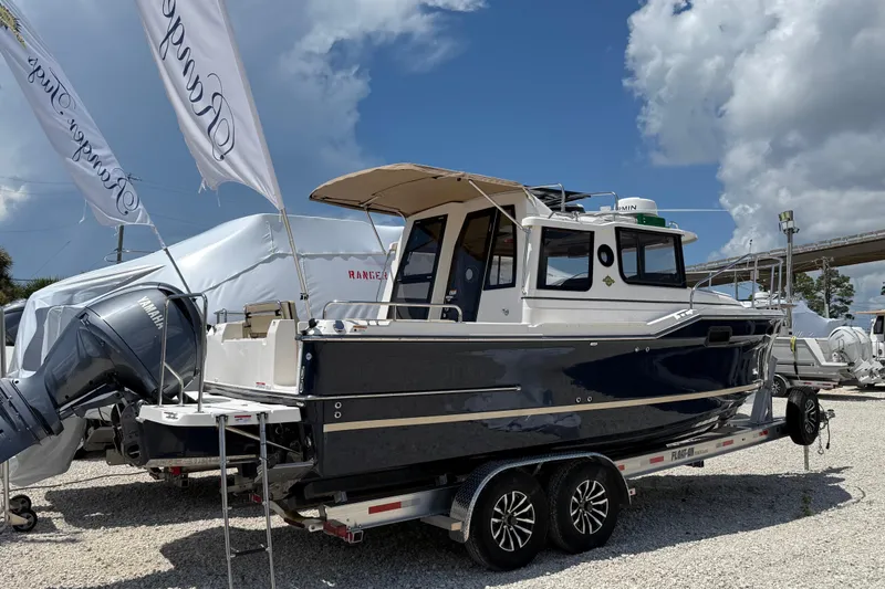 The Image of 2025 Ranger Tugs R-23 boat on trailer, displayed outdoors under a cloudy sky. - 0