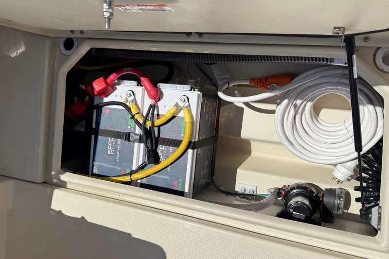 Slide: The Image of 2025 Ranger Tugs R-23 boat battery compartment with cables and coiled hose. - 17
