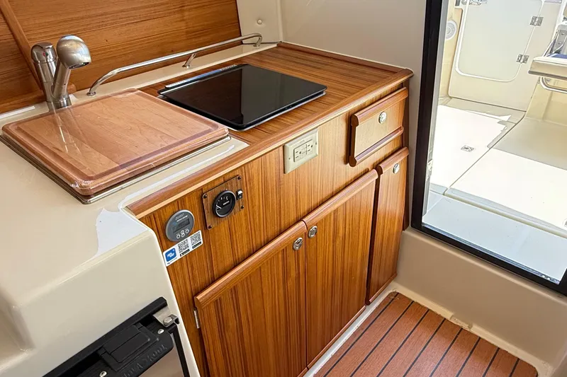 Slide: The Image of 2025 Ranger Tugs R-23 interior kitchen with wooden cabinetry and modern appliances. - 29