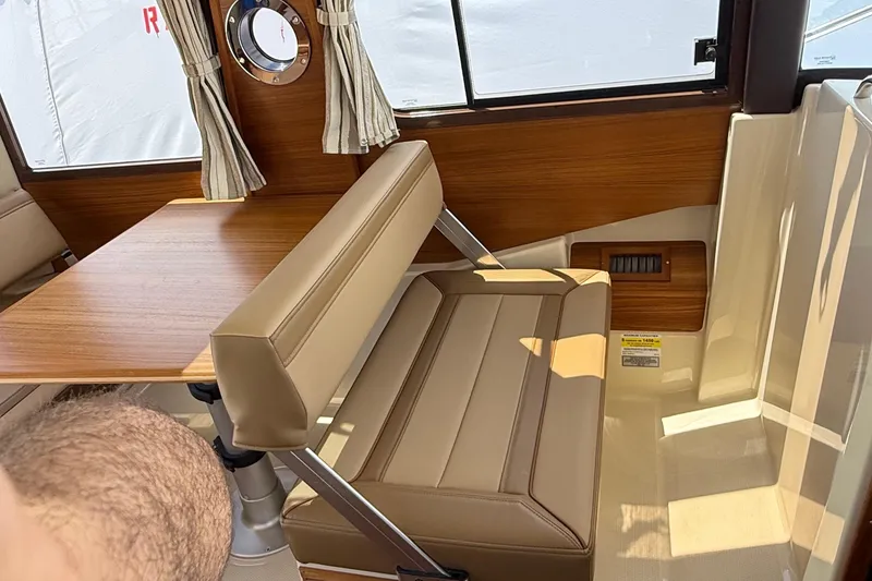 Slide: The Image of Interior of 2025 Ranger Tugs R-23, featuring a wooden table and beige seating. - 31