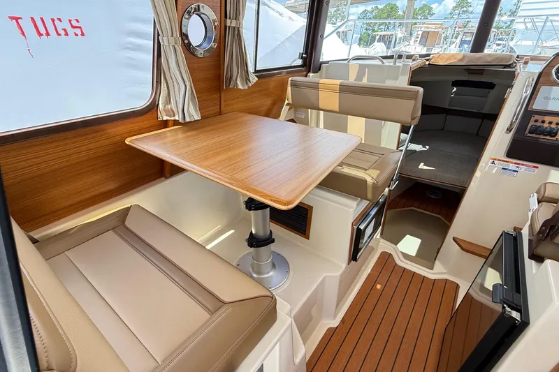 Slide: The Image of 2025 Ranger Tugs R-23 interior with wood table, beige seating, and nautical decor. - 38