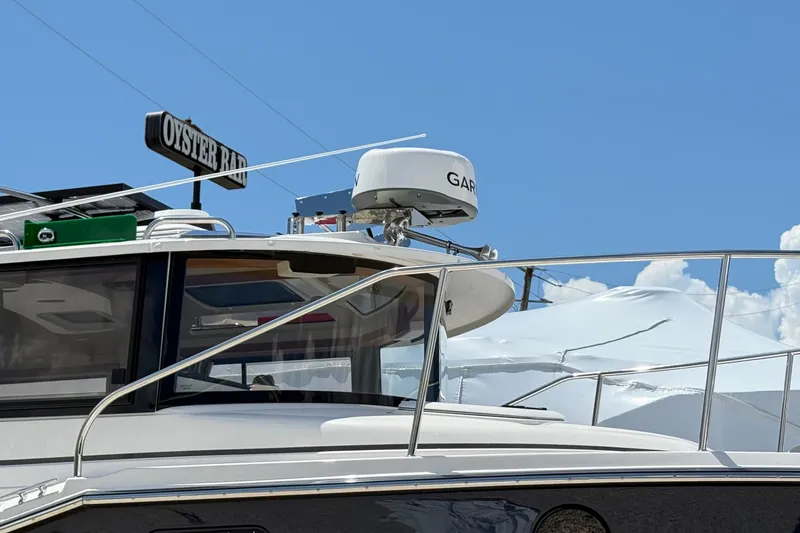 Slide: The Image of 2025 Ranger Tugs R-23 boat with radar, docked near Oyster Bar sign. - 5