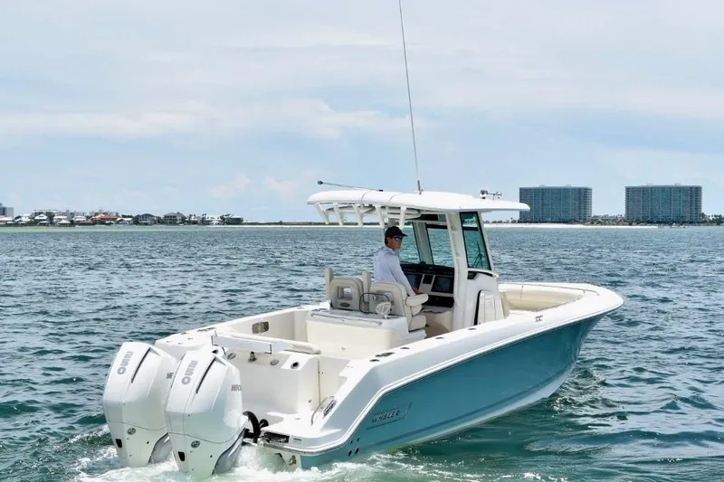 Slide: The Image of 2023 Boston Whaler 280 Outrage boat cruising on open water with cityscape background. - 5