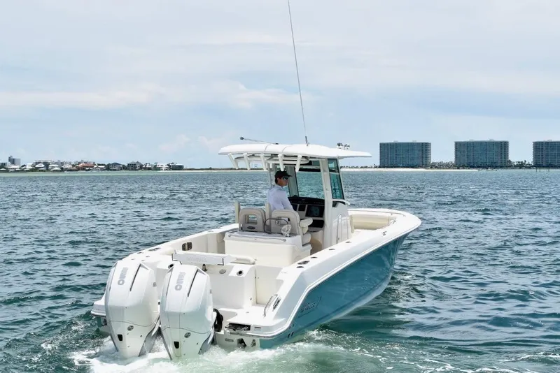 Slide: The Image of 2023 Boston Whaler 280 Outrage boat cruising on open water near coastal buildings. - 6