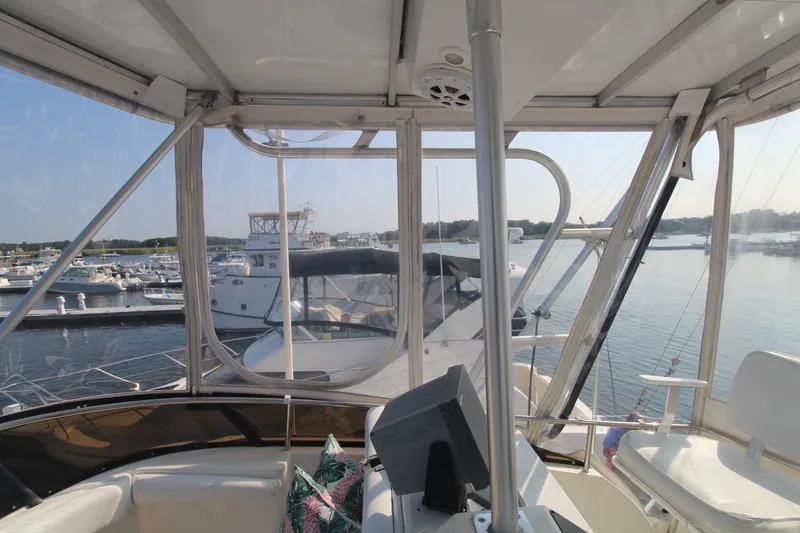 Slide: The Image of 1996 Silverton 41 Convertible yacht interior with marina view, featuring helm and seating area. - 16