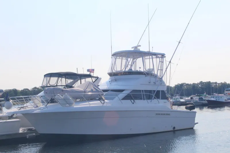 Slide: The Image of 1996 Silverton 41 Convertible yacht docked in a marina, featuring a spacious deck and flybridge. - 2