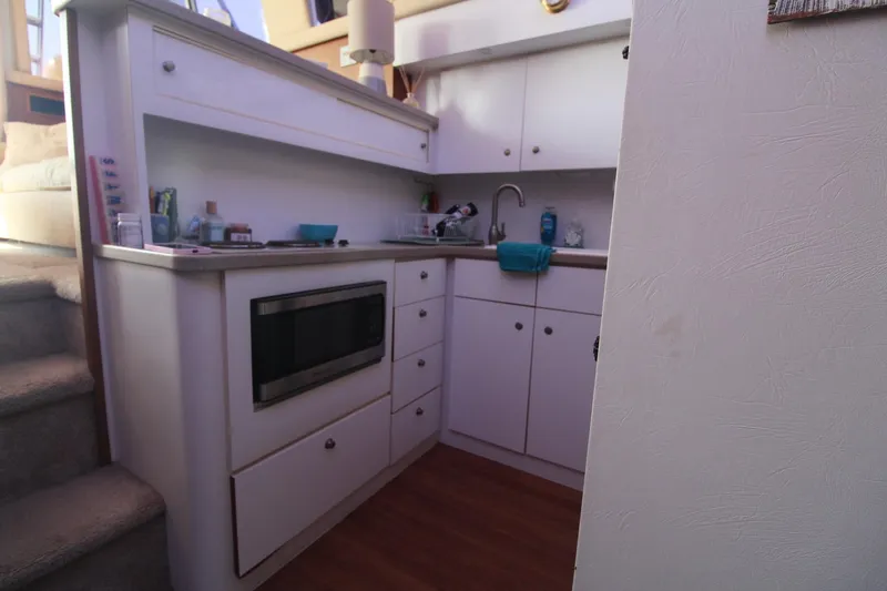 Slide: The Image of Compact kitchen area in a 1996 Silverton 41 Convertible boat, featuring a microwave and sink. - 46