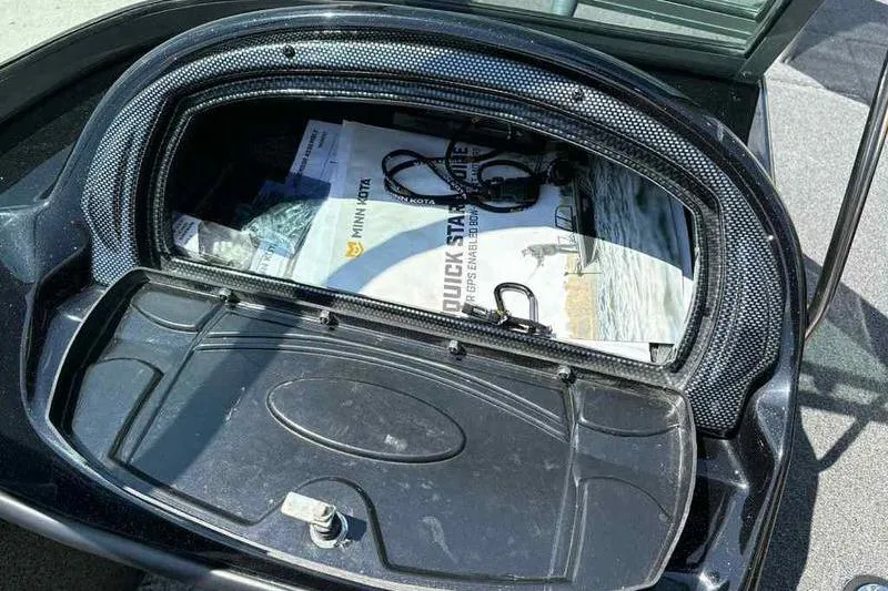 Slide: The Image of Open storage compartment in a 2017 Triton 168 DV boat with manuals and cables. - 13