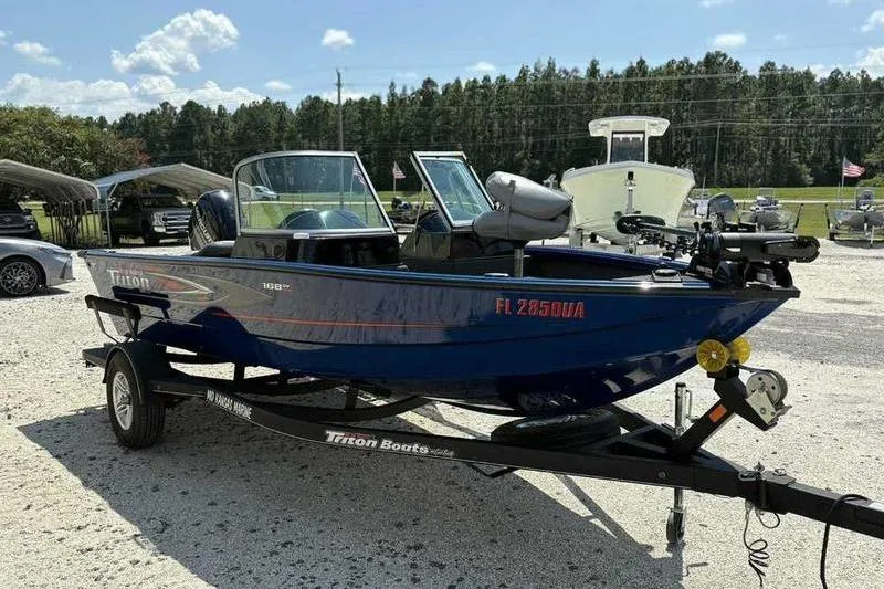 Slide: The Image of 2017 Triton 168 DV boat on trailer, parked outdoors under clear sky. - 7