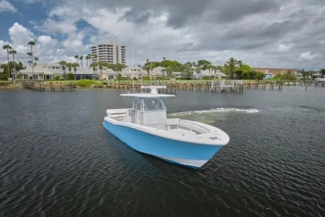 Slide: The Image of 2015 Invincible 36 boat cruising near a coastal town under cloudy skies. - 38