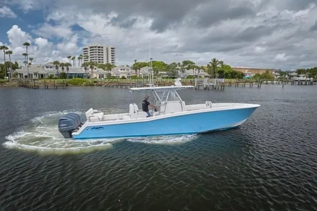Slide: The Image of 2015 Invincible 36 boat cruising on a calm waterway under cloudy skies. - 40