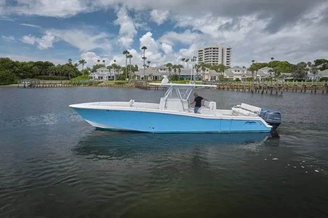 Slide: The Image of 2015 Invincible 36 boat on calm water with scenic coastal background. - 44