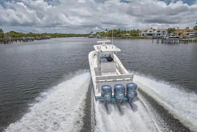 Slide: The Image of 2015 Invincible 36 boat cruising on a scenic waterway with triple engines. - 55