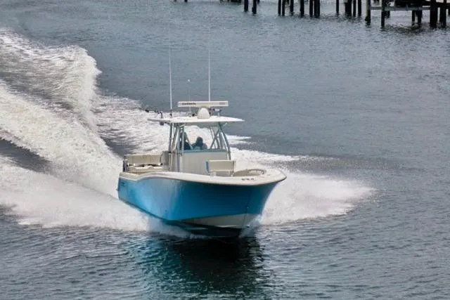 Slide: The Image of 2015 Invincible 36 boat cruising on water near docks. - 62