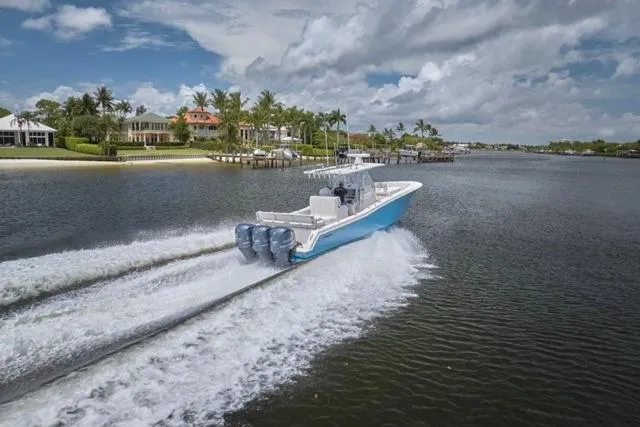 Slide: The Image of 2015 Invincible 36 boat cruising on a scenic waterway with waterfront homes. - 64
