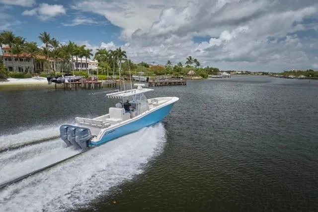 Slide: The Image of 2015 Invincible 36 boat cruising on a scenic waterway with palm trees. - 65
