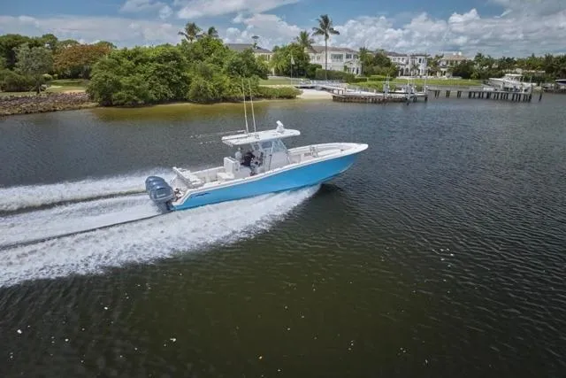 Slide: The Image of 2015 Invincible 36 boat cruising on a scenic waterway with lush greenery. - 66