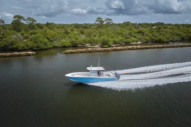 Slide: The Image of 2015 Invincible 36 boat cruising on a calm river with lush green shoreline. - 70